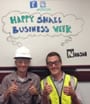 Two people giving thumbs-up infront of a whiteboard which says "Happy Small Business Week"