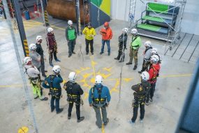 This example of a safety training shows workers wearing personal protective equipment gathered on a factory floor. .