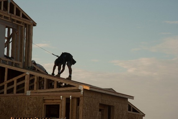 042722a Roofer working on a building with safety harness attached