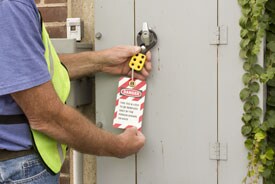 Worker holding a lockout/tagout tab which reads: DANGER- This tag and lock to be removed only by the person shown on back.