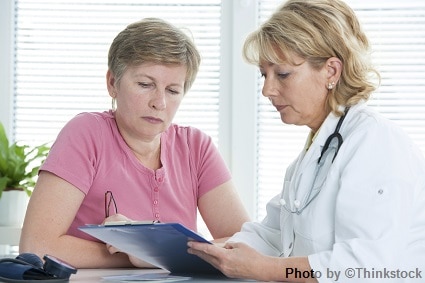 A female doctor talks to her patient while holding a chart