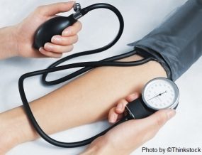 Two arms are visible with blood pressure being taken with a sphygmomanometer