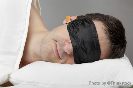 A man sleeping in bed with eye shades