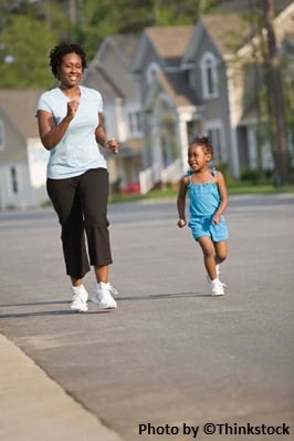 A mother and daughter smiling, jogging in a neighborhood