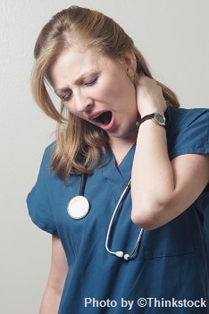 A tired nurse yawning with her hand on her neck yawning