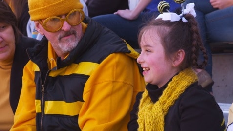 Father and daughter sitting in the stands at a football game.