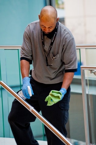 Man cleaning a stair railing in a conference center.