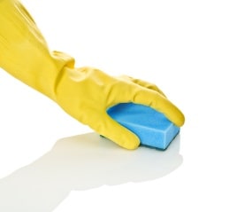Gloved hand cleaning surface with a sponge.