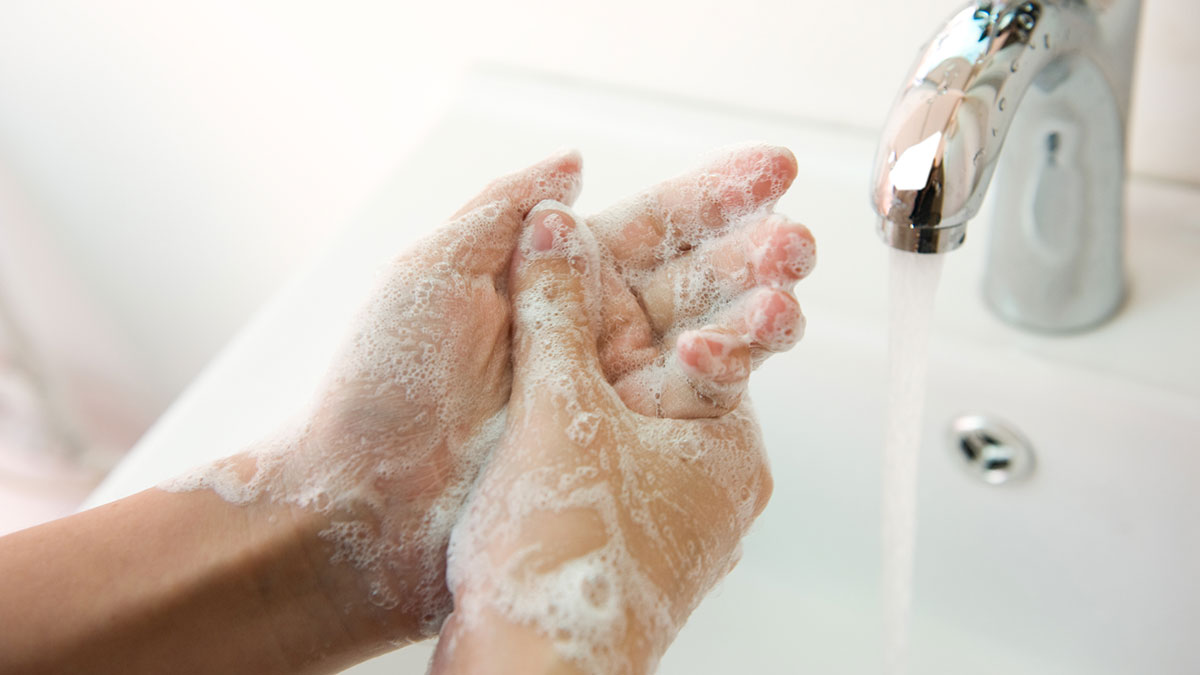 Washing of hands with soap under running water.