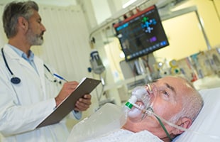 patient wearing oxygen mask on hospital bed with dr charting at bedside