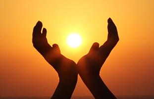 hands raised with sun cupped in shadow