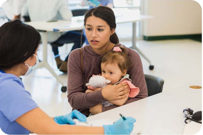 A mother consults with a healthcare provider while holding her baby.