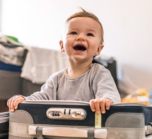 A smiling child sitting in a suitcase.