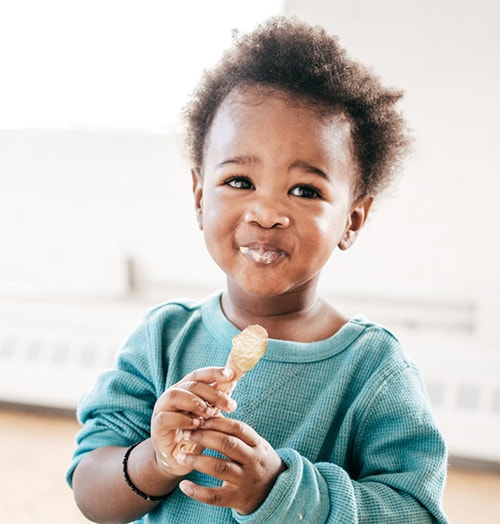 A young child to eating from a spoon.