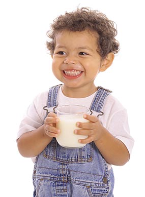 Un enfant de 12 mois tenant un petit pichet de lait de vache. À 12 mois, vous pouvez commencer à donner à votre enfant du lait de vache qui a été pasteurisé et enrichi en vitamine D.