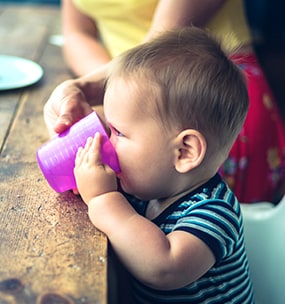 An older infant drinking from a cup. 