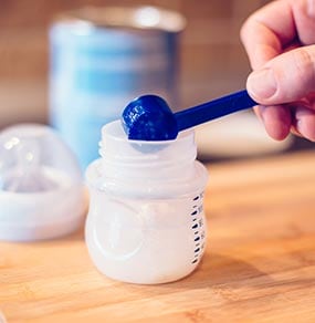 A mother scooping infant formula out from the container. Always carefully read and follow the instructions on the infant formula container. 
