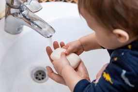 Toddler washing hands with soap and water