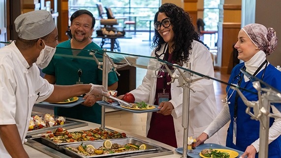 Employees getting food in a hospital cafeteria.