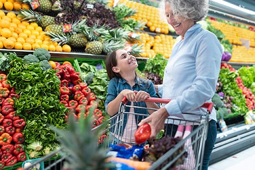 Girl shopping with her grandmother in the produce aisle