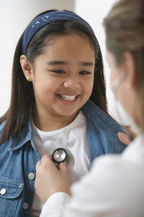 Photo: A doctor placing a stethoscope on a girl's chest.