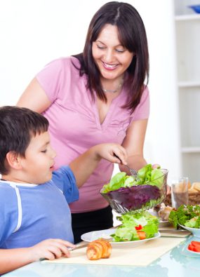 Photo: Mother serving fresh healthy salad to her son