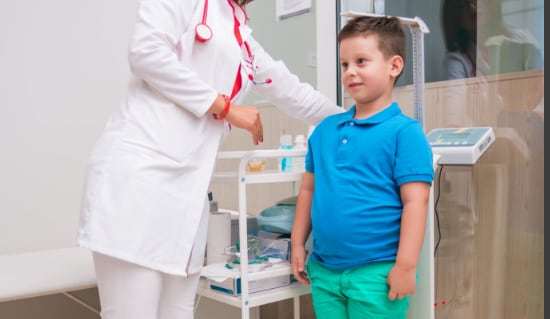 Photograph of a child in the doctor's office; the doctor is measuring the child's height.