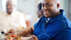 Man getting a serving of fruit from a large bowl.