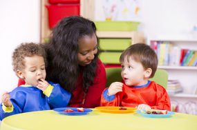 Children eating fruit at a nursery with their carer