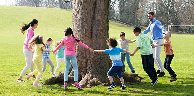 Children and adults dancing around a tree