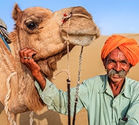 man standing next to a camel