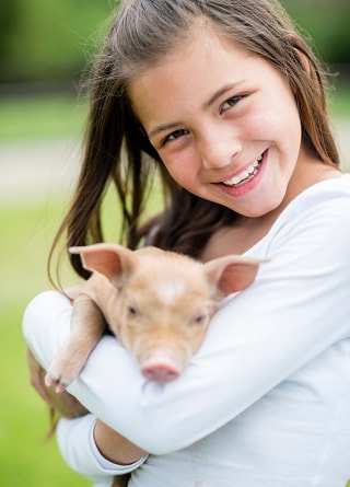 Little girl holding a baby pig