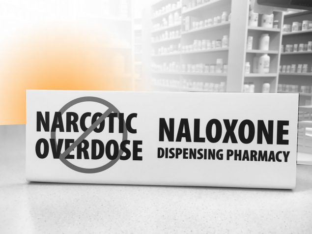 photo of a pharmacy with a naloxone sign