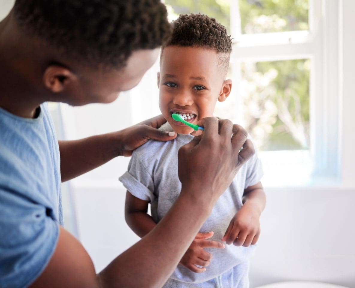 African American Man brushing African American toddler's teeth