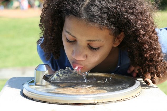Girl drinking from water fountain in the park