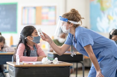 School nurse wearing PPE taking student's temperature