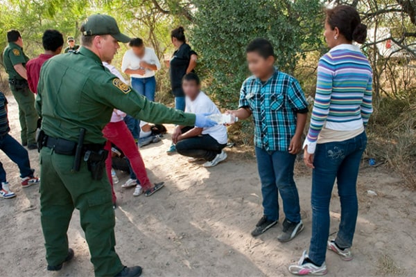Border patrol agent giving paper to child and mother
