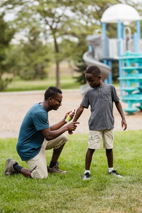 Parent applying insect repellent to a child.