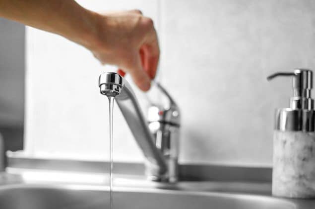 Hand opens the water tap