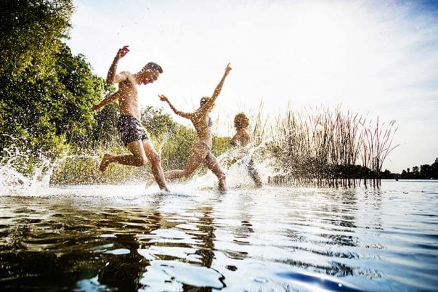 Friends Splashing In Water At Lake Together