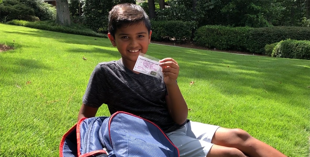 A boy holding his backpack emergency card