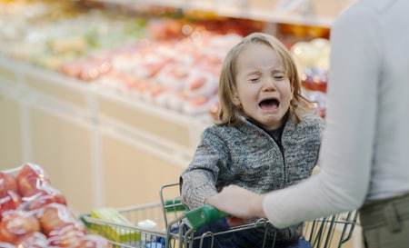child crying in shopping cart in supermarket