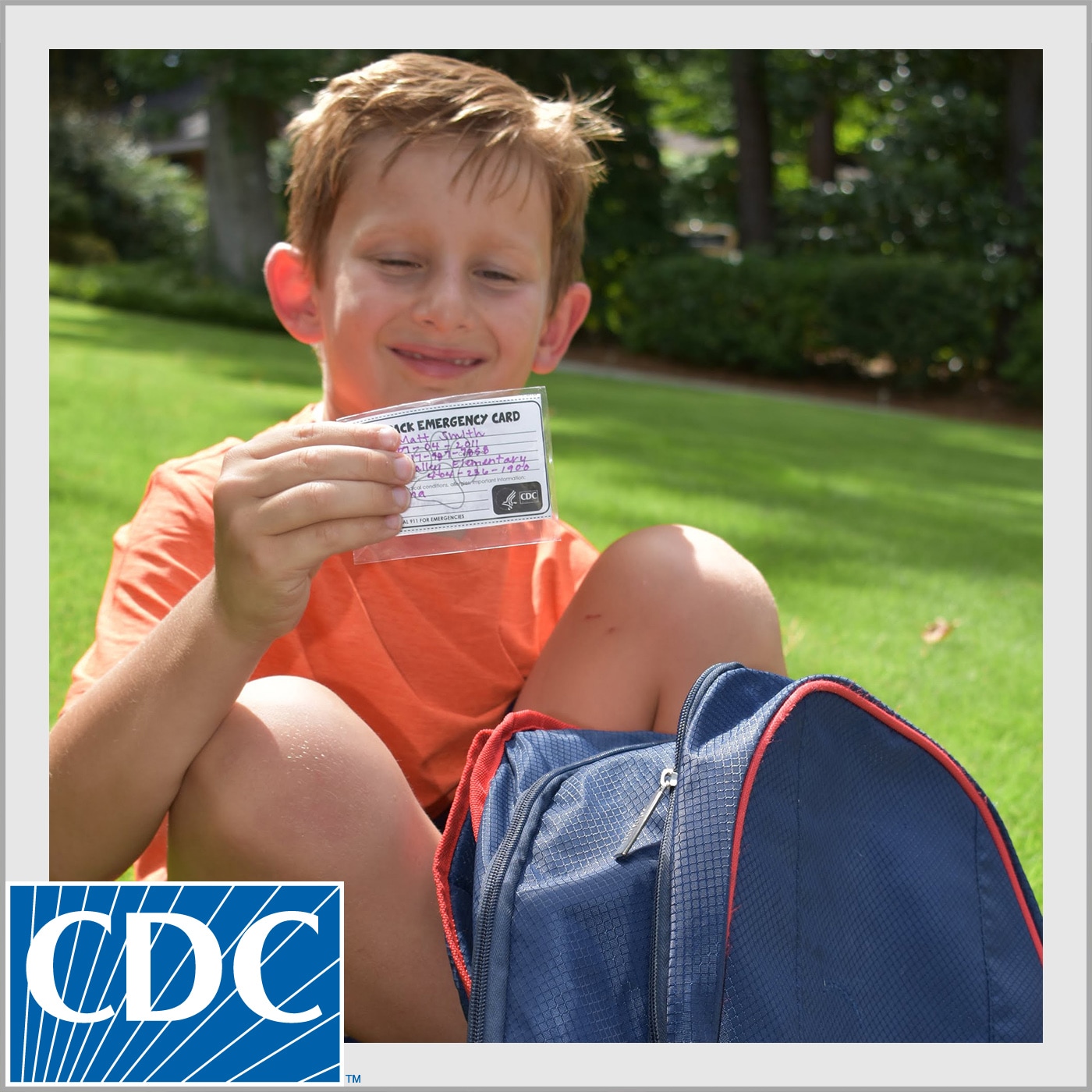Child holding his backpack emergency card