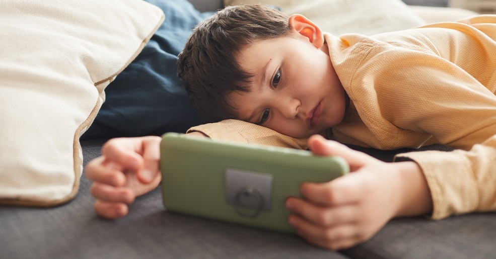 Boy laying on floor looking at phone