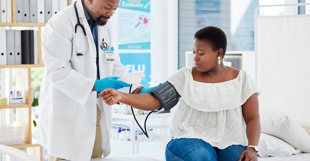 Male doctor checking blood pressure of female patient