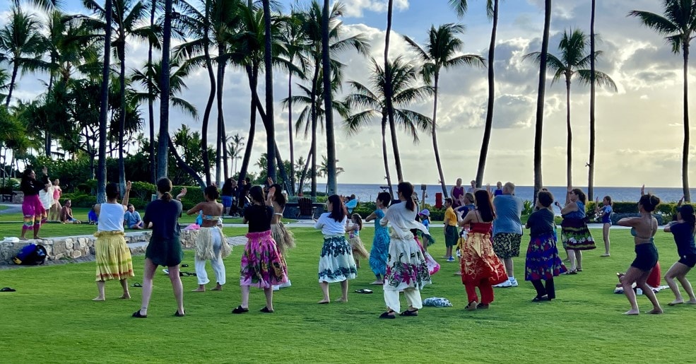 A class of Hawaiians Hula dancing together in a park.