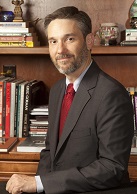 Sam-Posner A photograph of Dr Samuel F. Posner appears behind a desk in front of a bookshelf.