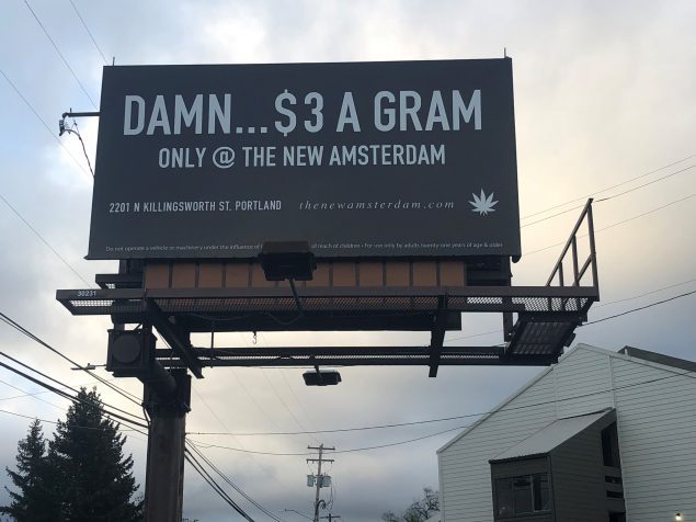 A photograph shows a billboard that reads “Damn . . . $3 A Gram, Only @ the New Amsterdam. 2201 N Killingsworth St. Portland, thenewamsterdam.com”. In small type at the bottom of the billboard is “Do not operate a vehicle or heavy machinery under the influence of [text obscured by a light fixture] of reach of children. For use only by adults twenty-one years of age or older”.