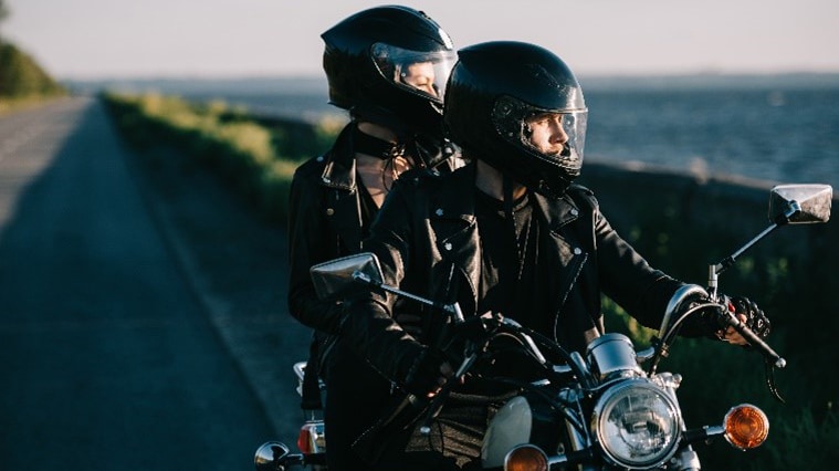 A couple on a motorcycle wearing helmets and jackets