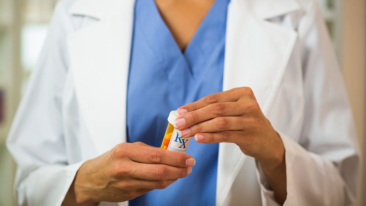 Closeup of pharmacist holding pills in hand.